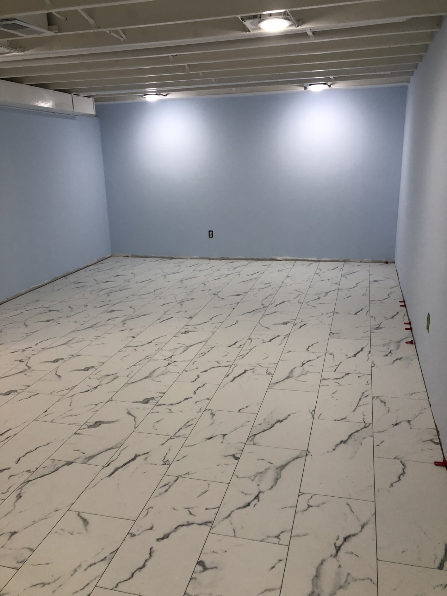 New tile flooring and wall tile with fresh baseboard in a remodeled room