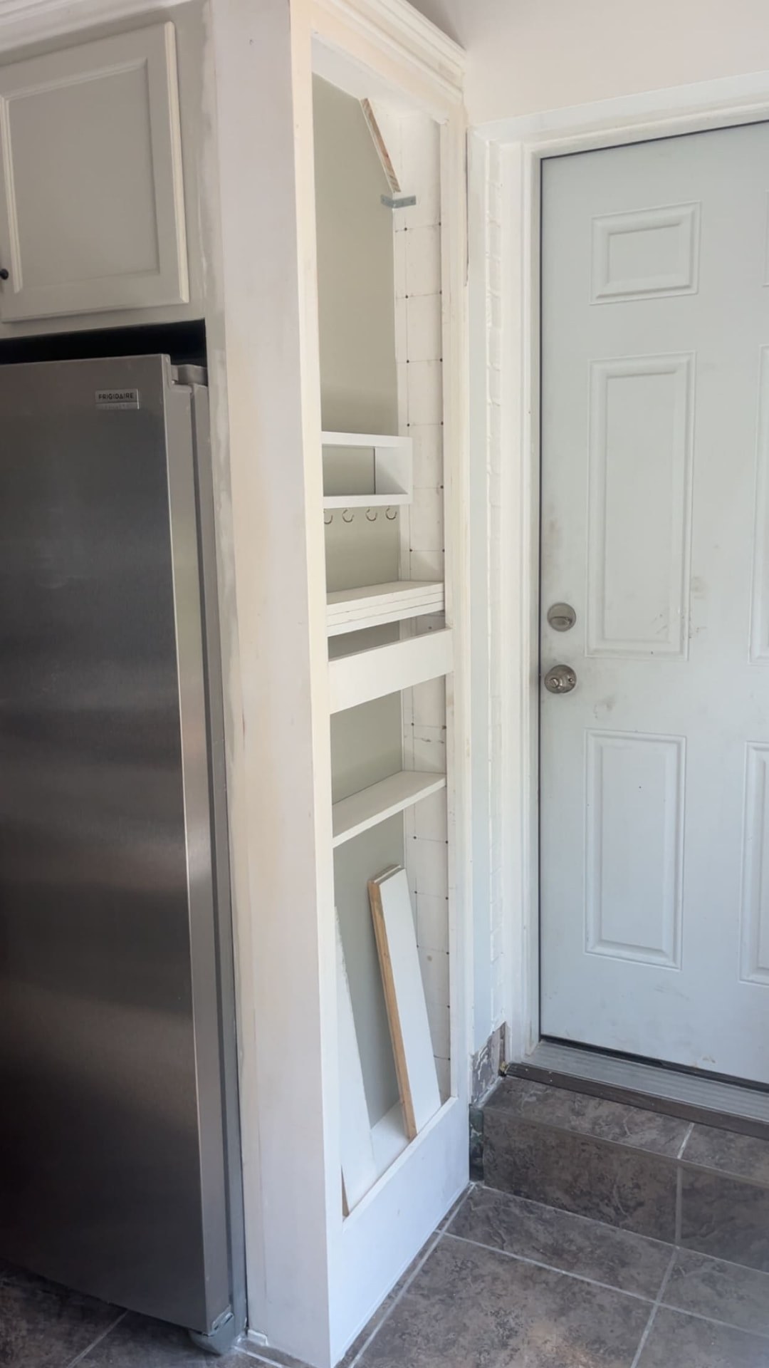 Custom built-in pantry shelving framed beside a kitchen entry door