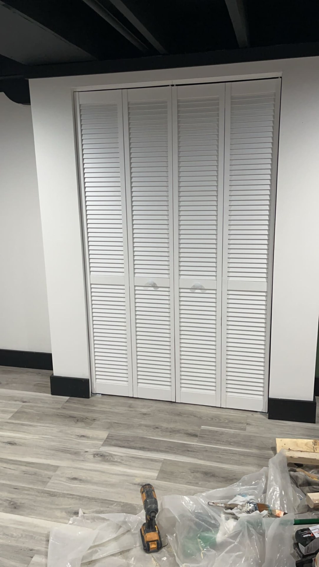 White louvered bi-fold closet doors installed in a finished basement