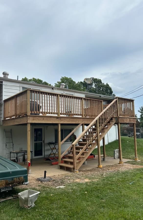 Elevated backyard deck with full railing and stairs down to the patio