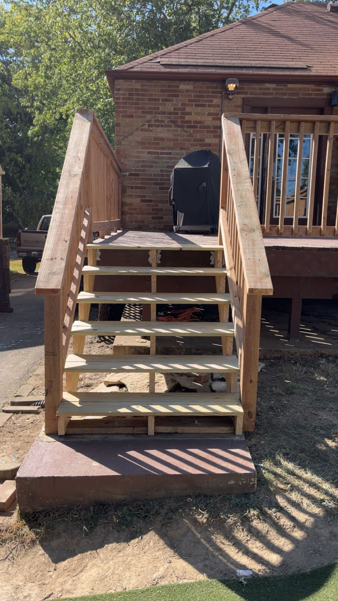 New pressure-treated deck stairs and railing on a brick ranch home