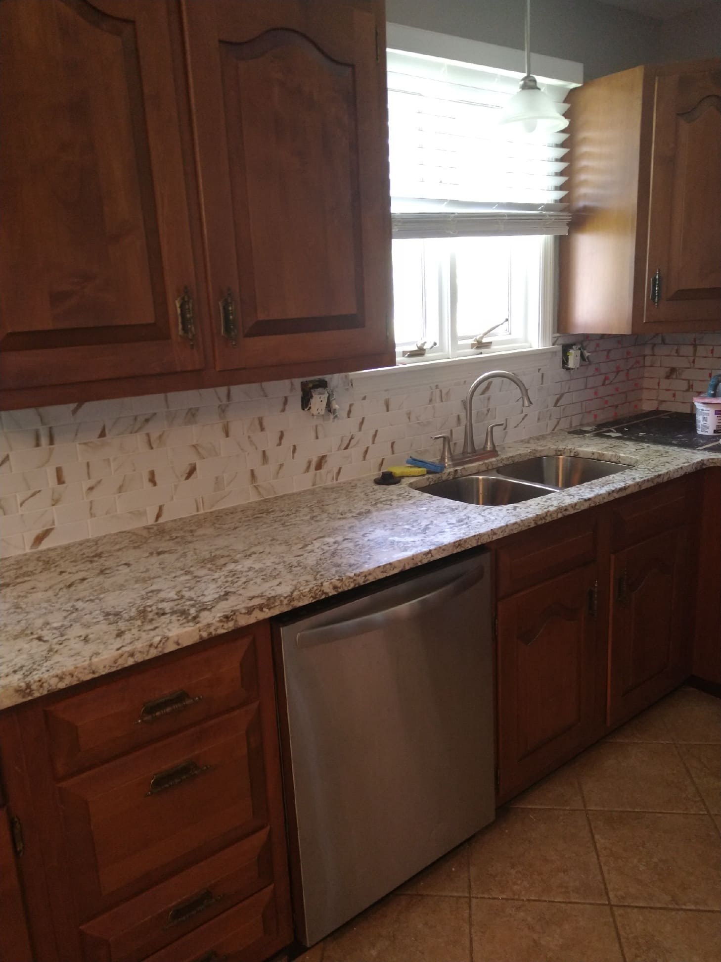 New granite countertop, sink and tile backsplash installed in a kitchen remodel